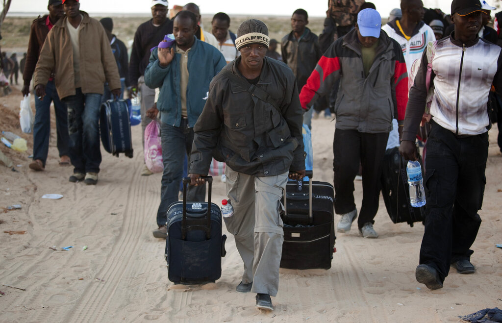 Des hommes du Ghana arrivent dans un camp de réfugiés après avoir traversé la frontière libyenne, près d'un camp de réfugiés mis en place pour les personnes déplacées qui ont récemment traversé la frontière tunisienne, fuyant les troubles en Libye, à Ras Ajdir, en Tunisie, le dimanche 20 mars 2011. Plus de 250 000 travailleurs migrants ont quitté la Libye pour les pays voisins, principalement la Tunisie et l'Égypte, au cours des trois dernières semaines. (AP Photo/Emilio Morenatti)